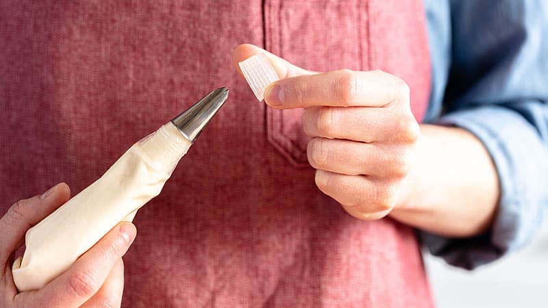 person adding a piping tip and coupler to a piping bag