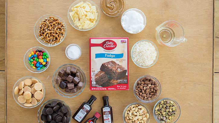 Betty Crocker fudge brownie mix, front of package and a variety of mix-in ingredients in bowls