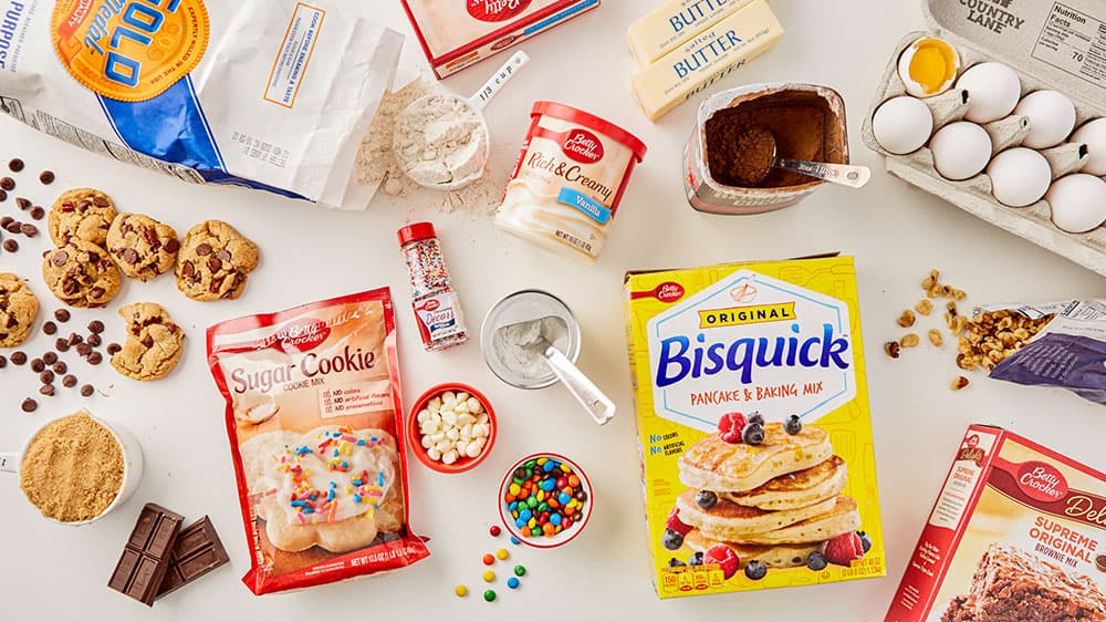 Baking ingredients including Betty Crocker Sugar cookie mix, front of package; rich & creamy vanilla frosting, front of package; original Bisquick, front of package; butter and eggs